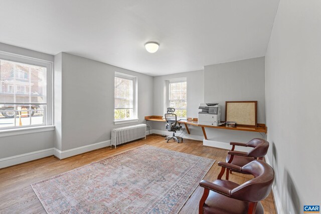 office featuring wood finished floors, baseboards, and radiator heating unit
