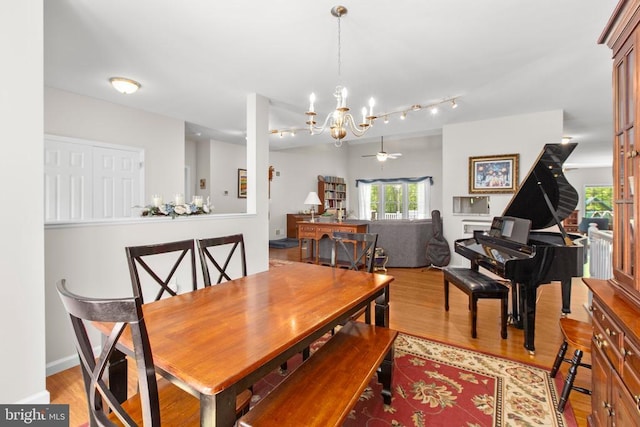 dining space featuring track lighting, light wood-style floors, and a notable chandelier