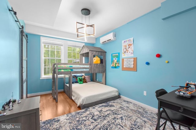 bedroom with wood finished floors, baseboards, and a wall mounted AC