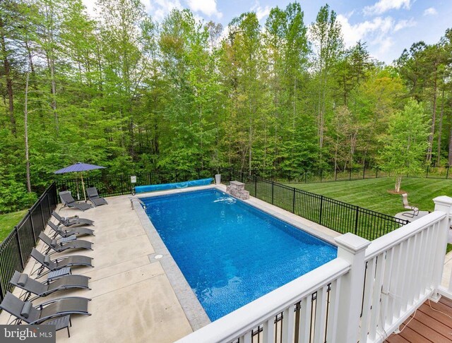 view of swimming pool with a yard, a wooded view, a patio, a fenced backyard, and a fenced in pool