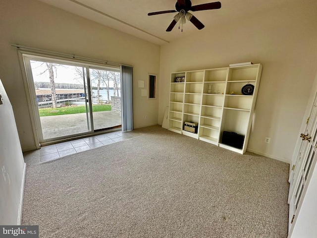 carpeted empty room with ceiling fan, tile patterned flooring, and baseboards