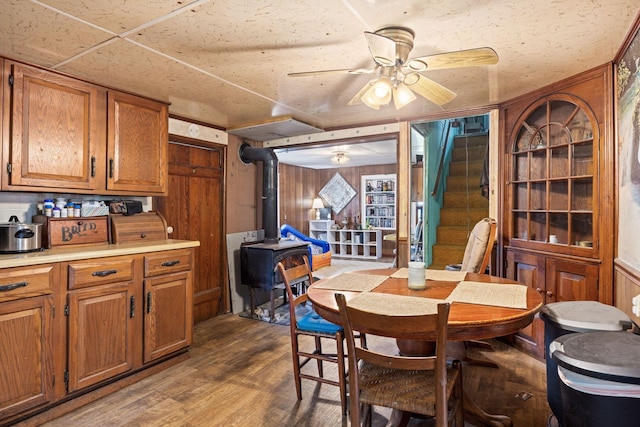 6596 Mayberry Rd, Singers Glen, VA 22850 - dining room featuring a wood stove, ceiling fan, wood finished floors, wooden walls, and stairs