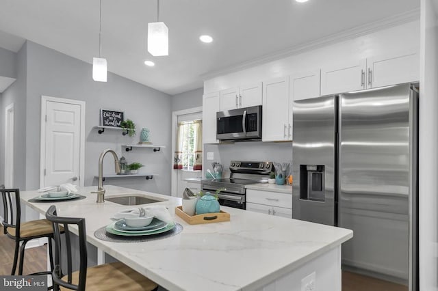  - kitchen with appliances with stainless steel finishes, white cabinets, a kitchen bar, decorative light fixtures, and a center island with sink