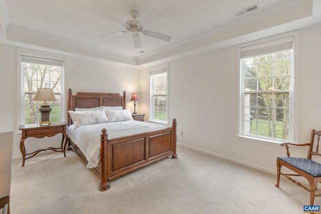 bedroom with visible vents, crown molding, light carpet, a tray ceiling, and baseboards