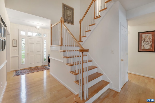 foyer entrance featuring stairway, baseboards, and wood finished floors