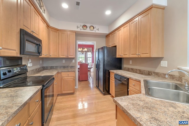kitchen featuring a sink, light brown cabinets, light wood-type flooring, visible vents, and black appliances