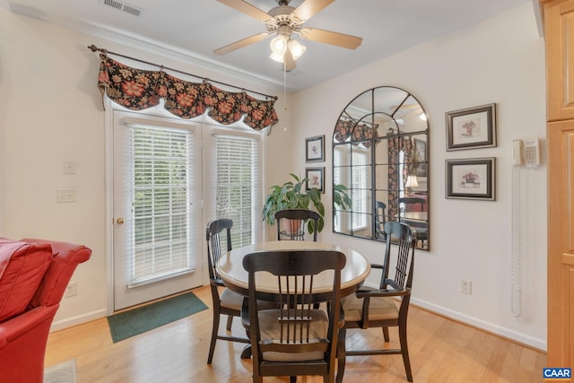 dining space featuring light wood finished floors, visible vents, baseboards, and ceiling fan