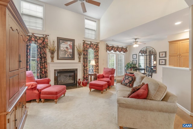 living area with a fireplace, baseboards, a towering ceiling, ceiling fan, and recessed lighting