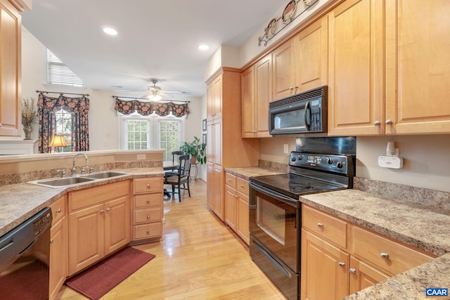 kitchen with a ceiling fan, light brown cabinets, light wood finished floors, a sink, and black appliances
