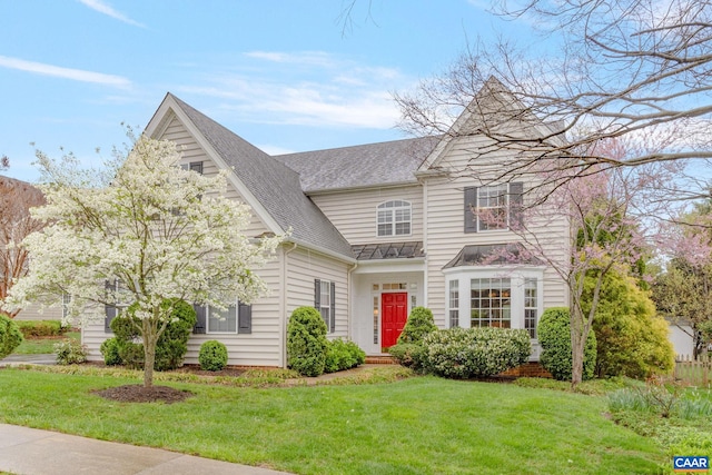 traditional home with a shingled roof, metal roof, a front yard, and a standing seam roof