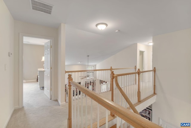 hall featuring baseboards, light carpet, an upstairs landing, and visible vents
