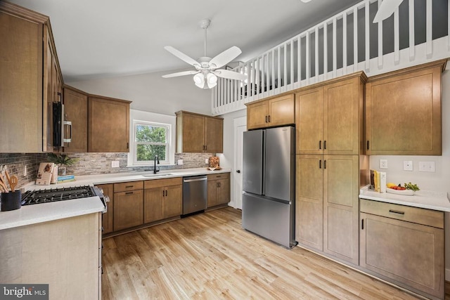  - kitchen with stainless steel appliances, light wood-style flooring, decorative backsplash, a ceiling fan, and high vaulted ceiling