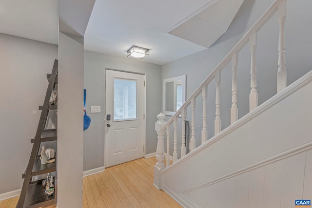 entryway with wood finished floors, baseboards, and stairs