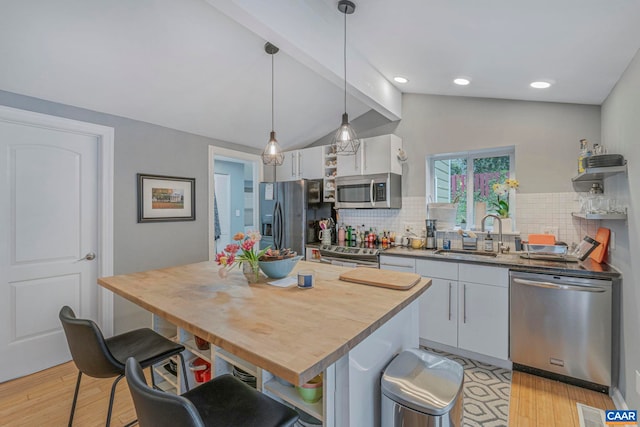 kitchen with stainless steel appliances, a sink, open shelves, a kitchen breakfast bar, and light wood-style floors