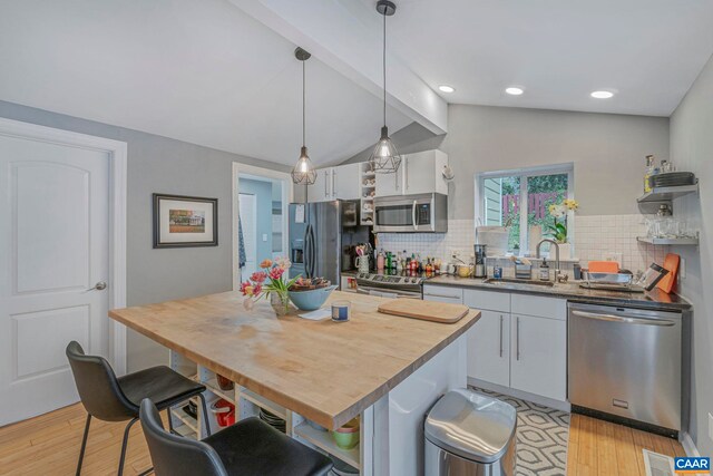 316 6 1/2 St, Charlottesville, VA 22903 - kitchen with stainless steel appliances, a sink, open shelves, a kitchen breakfast bar, and light wood-style floors