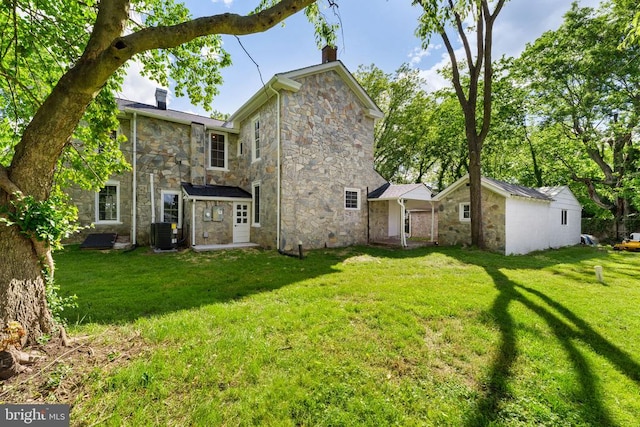 105 Washington St E, Remington, VA 22734 - rear view of house with stone siding, a chimney, a yard, and central AC