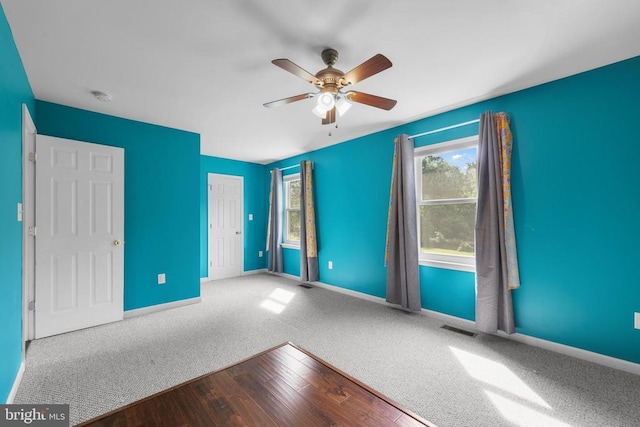  - unfurnished bedroom with wood finished floors, a closet, a ceiling fan, and carpet