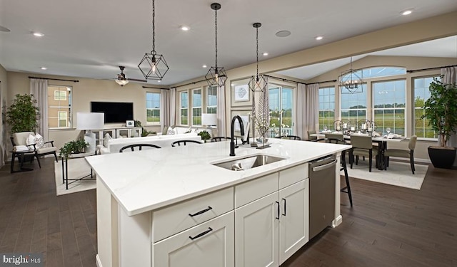 kitchen with a sink, open floor plan, a kitchen island with sink, decorative light fixtures, and dark wood-type flooring
