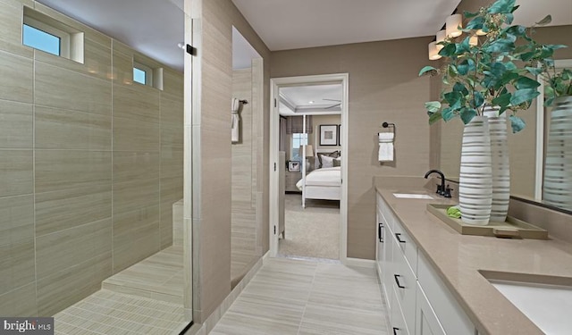ensuite bathroom with double vanity, tiled shower, and tile patterned floors