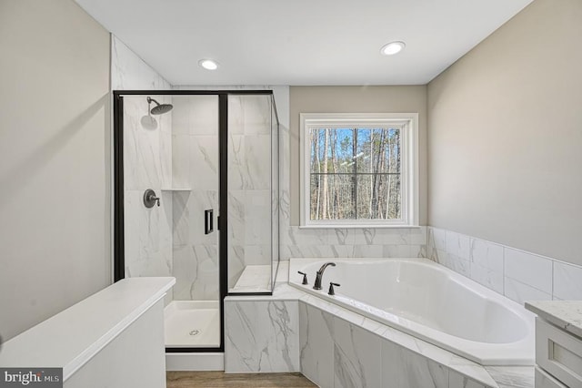 bathroom featuring a marble finish shower, recessed lighting, and a bath