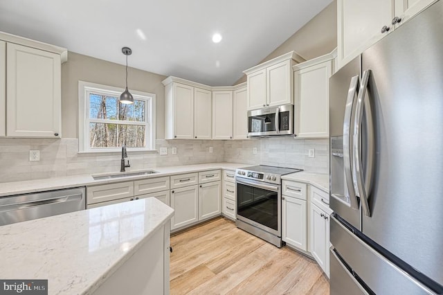 kitchen featuring a sink, stainless steel appliances, decorative light fixtures, light wood finished floors, and decorative backsplash