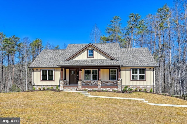 view of front of home featuring a porch, roof with shingles, and a front lawn