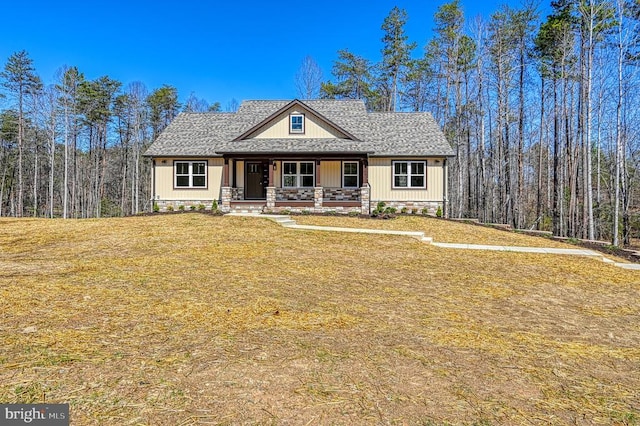 view of front of house with a porch, a shingled roof, and a front yard
