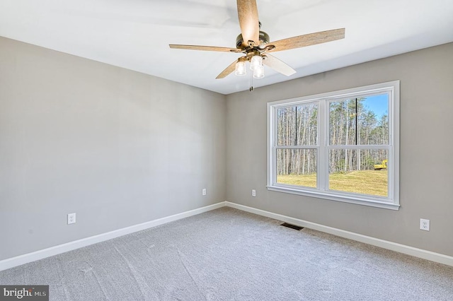carpeted spare room with baseboards, visible vents, and a ceiling fan