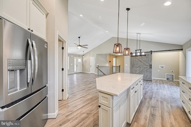 kitchen featuring stainless steel refrigerator with ice dispenser, vaulted ceiling, light wood-style flooring, a kitchen island, and baseboards
