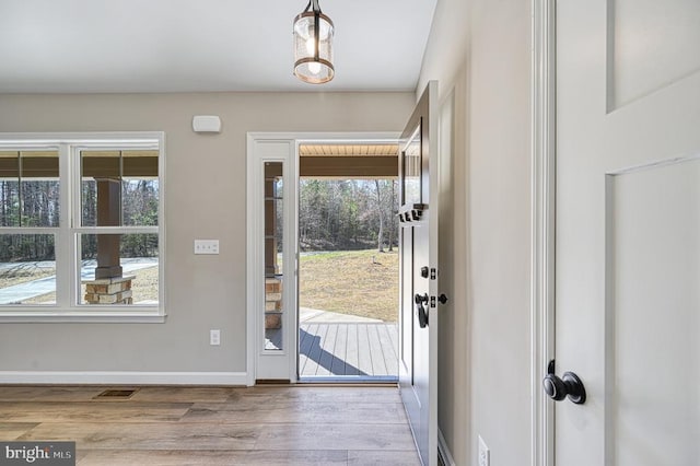 entryway with baseboards, visible vents, and wood finished floors