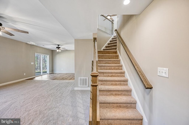 staircase with visible vents, baseboards, a ceiling fan, and carpet floors