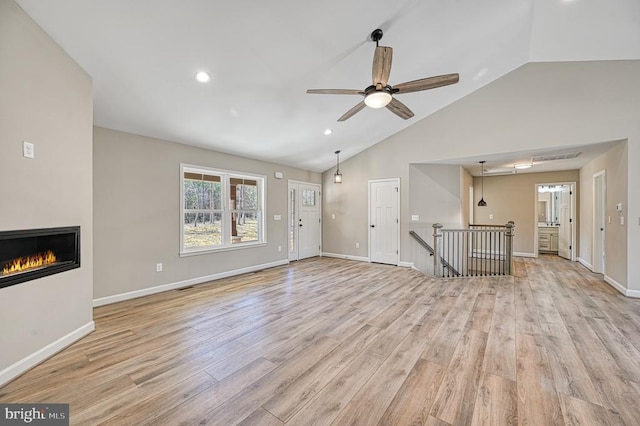 unfurnished living room with a ceiling fan, recessed lighting, baseboards, a glass covered fireplace, and light wood-type flooring