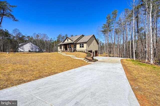 view of front of house featuring a front lawn, driveway, and covered porch
