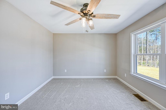 carpeted spare room with baseboards, ceiling fan, and visible vents