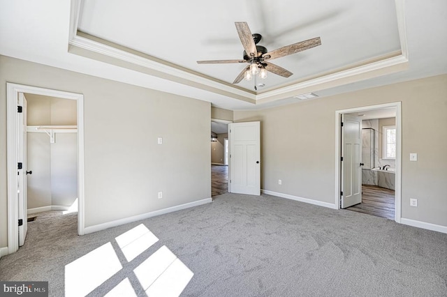 unfurnished bedroom with a tray ceiling, crown molding, and carpet floors