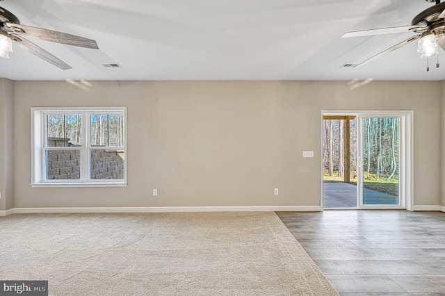 spare room featuring baseboards, visible vents, ceiling fan, and wood finished floors