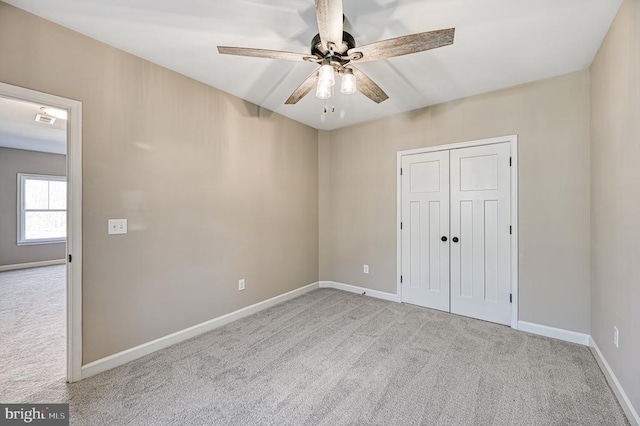 unfurnished bedroom with baseboards, carpet flooring, a closet, and a ceiling fan