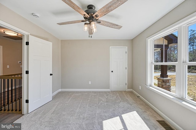 interior space with light carpet, baseboards, visible vents, and multiple windows