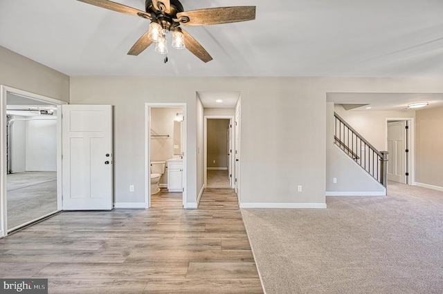 unfurnished bedroom featuring baseboards, ensuite bathroom, light wood-style flooring, and ceiling fan