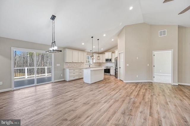 kitchen with visible vents, open floor plan, a center island, light countertops, and appliances with stainless steel finishes