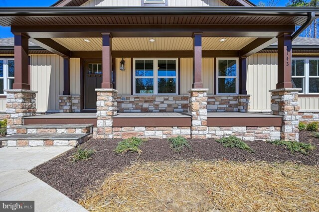 entrance to property featuring stone siding, covered porch, and board and batten siding