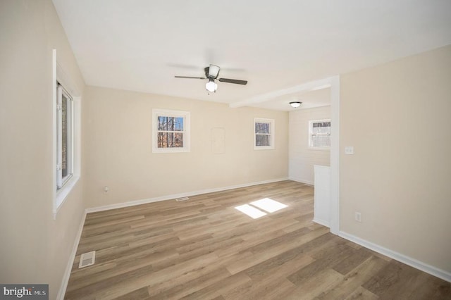 empty room with baseboards, ceiling fan, and light wood-type flooring