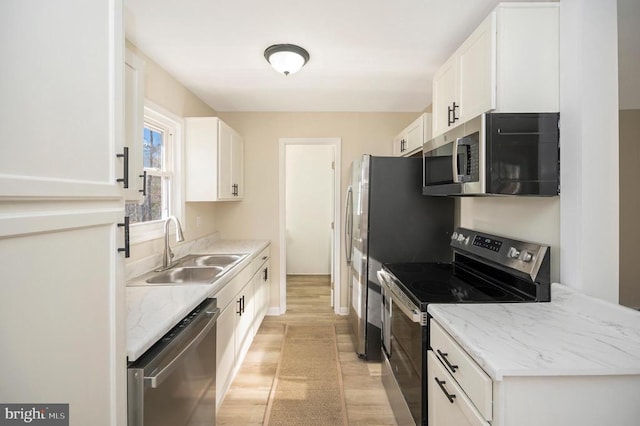 kitchen with stainless steel appliances, a sink, light wood-type flooring, and white cabinets