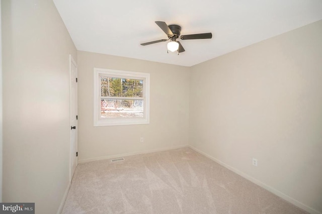 empty room with a ceiling fan, light colored carpet, and baseboards