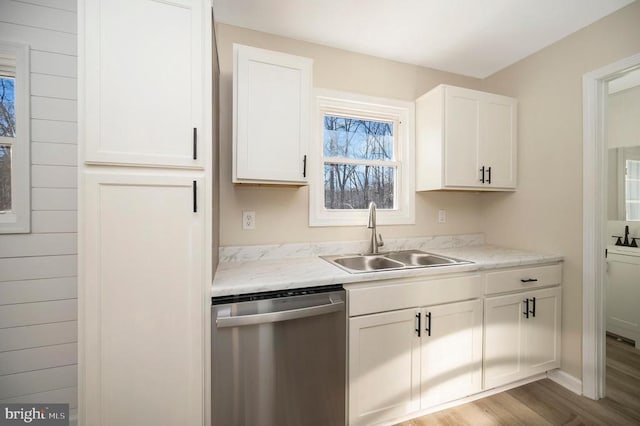 kitchen with dishwasher, a sink, light wood-style flooring, and white cabinets