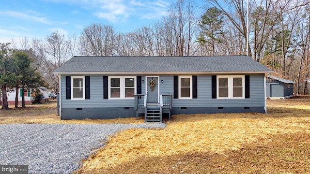 view of front of home featuring a shed, a shingled roof, crawl space, and an outdoor structure