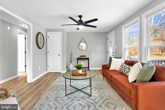 living room featuring light wood-style floors, baseboards, and a ceiling fan