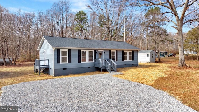 view of front facade featuring crawl space, roof with shingles, gravel driveway, and an outdoor structure