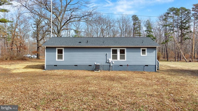 back of property featuring crawl space, a shingled roof, and a yard