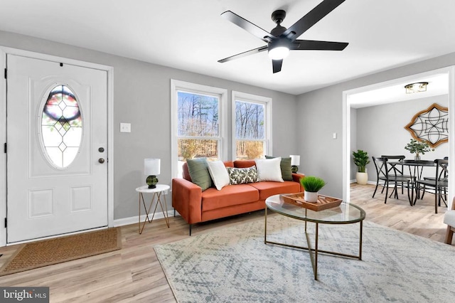 foyer entrance with light wood-type flooring, ceiling fan, and baseboards